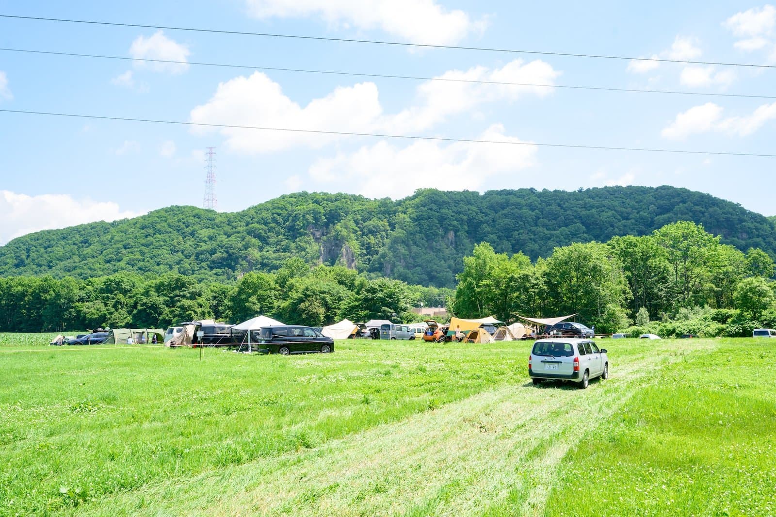 牧草地のオートキャンプエリアと山並み
